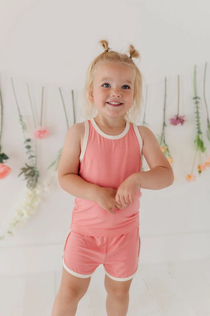 Coral pink kids track set: sleeveless tank and shorts, white trim.