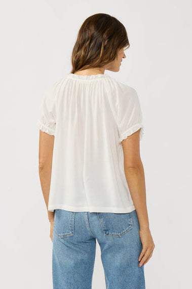 Woman wearing a white blouse and blue jeans on a plain background