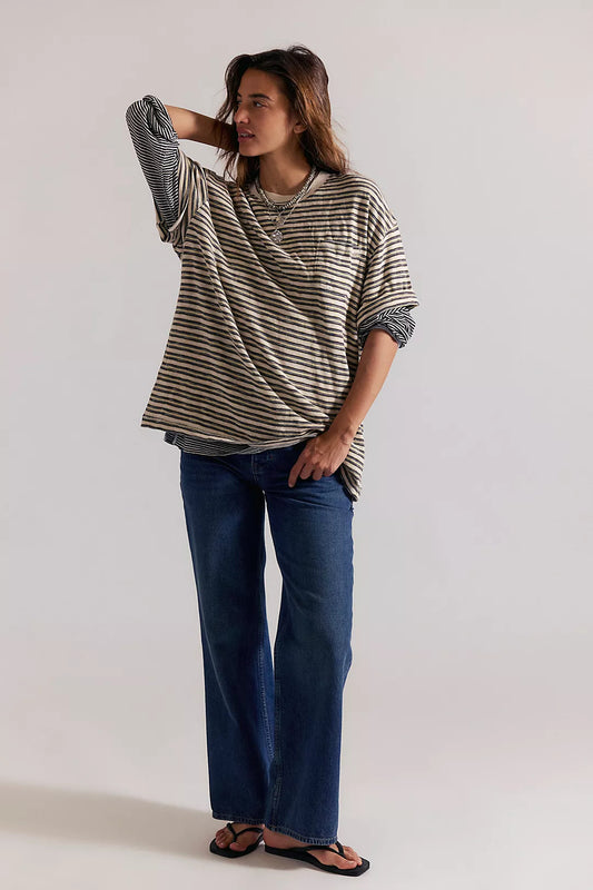 Woman wearing a striped shirt and blue jeans against a plain background
