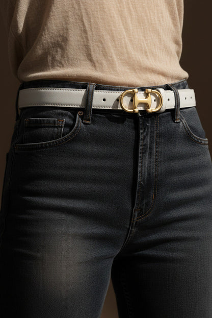Person wearing black jeans and a beige belt with a gold buckle on a brown background