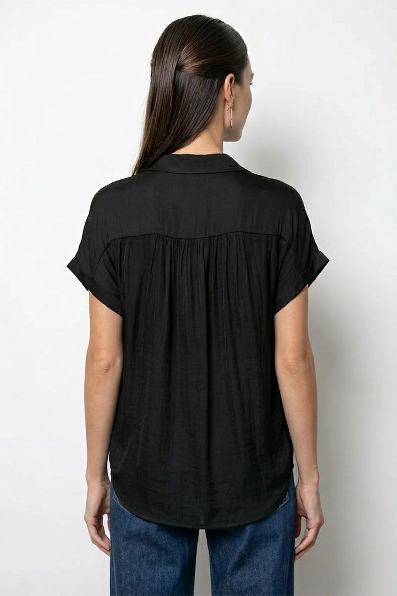 Back view of person wearing a black short-sleeve blouse against a white background