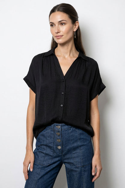 Woman wearing a black blouse and blue jeans against a white background
