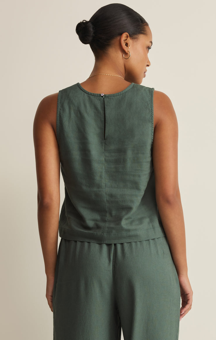 Woman wearing a green sleeveless top and pants set on a beige background