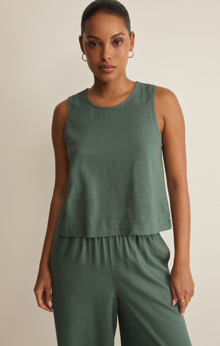 Woman wearing a green sleeveless top and pants against a beige background