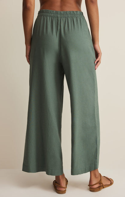 Green wide-leg linen pants worn by a person on a beige background