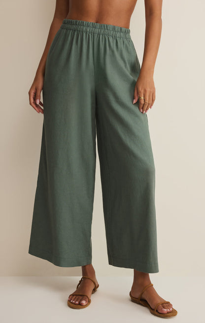 Person wearing green wide-leg linen pants on a plain background