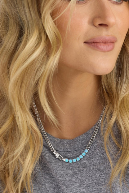 Close-up of a woman wearing a silver chain necklace with turquoise beads.