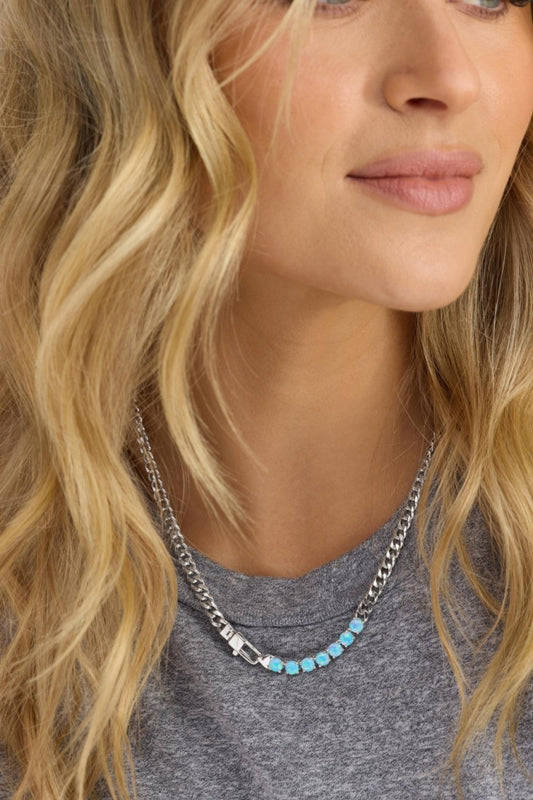 Close-up of a woman wearing a silver chain necklace with turquoise beads.