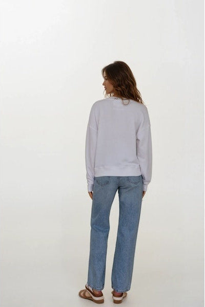 Woman wearing a white sweatshirt and blue jeans on a white background