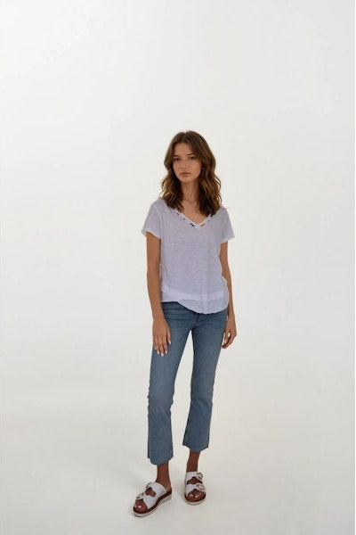 Woman wearing a white vneck and jeans on a white background