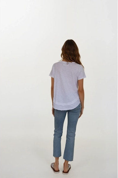Woman wearing a white t-shirt and blue jeans on a white background facing backward 