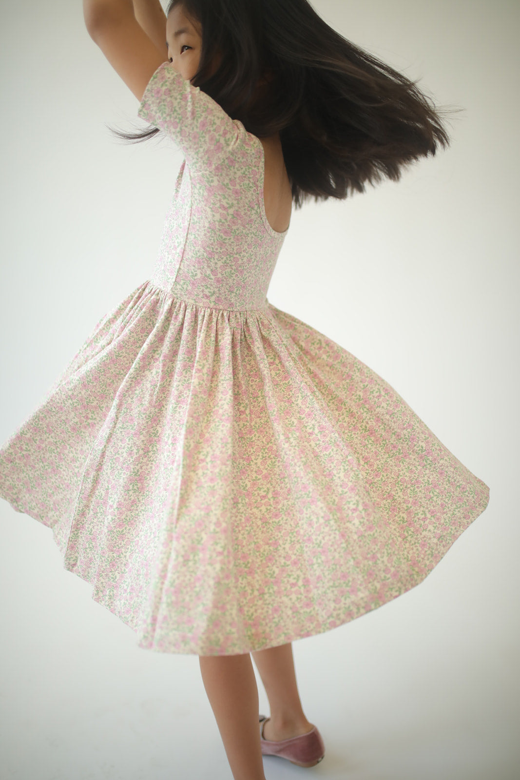 Girls twirl dress in pink speckled floral print, twirl flare skirt, side view.