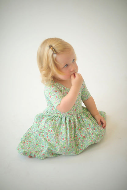 Girls green floral twirl dress, seated side view, gathered waist flares