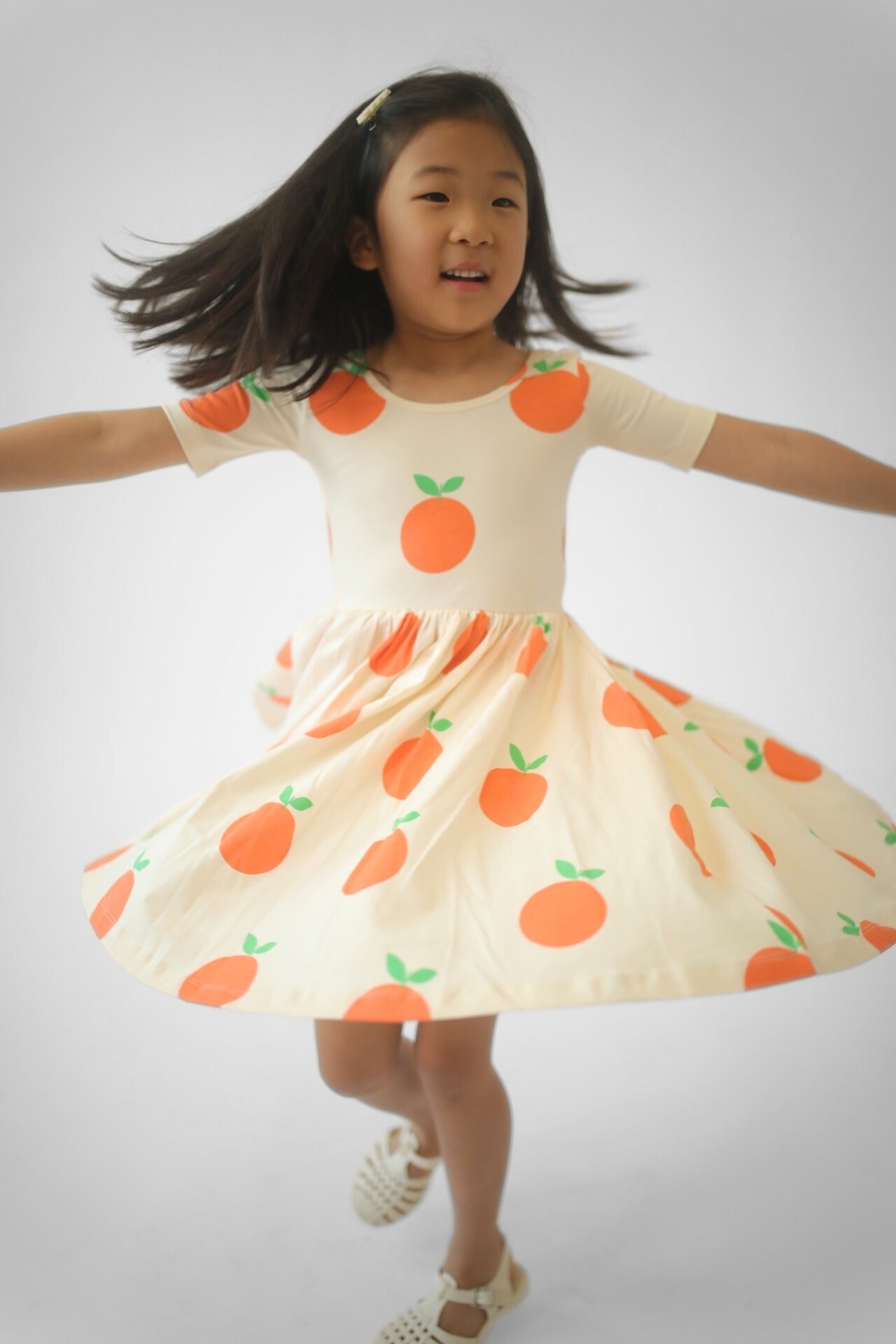 Girls orange fruit print twirl dress, front view, flared twirly skirt