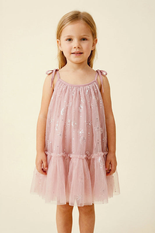 Young girl wearing a pink dress with floral patterns on a beige background