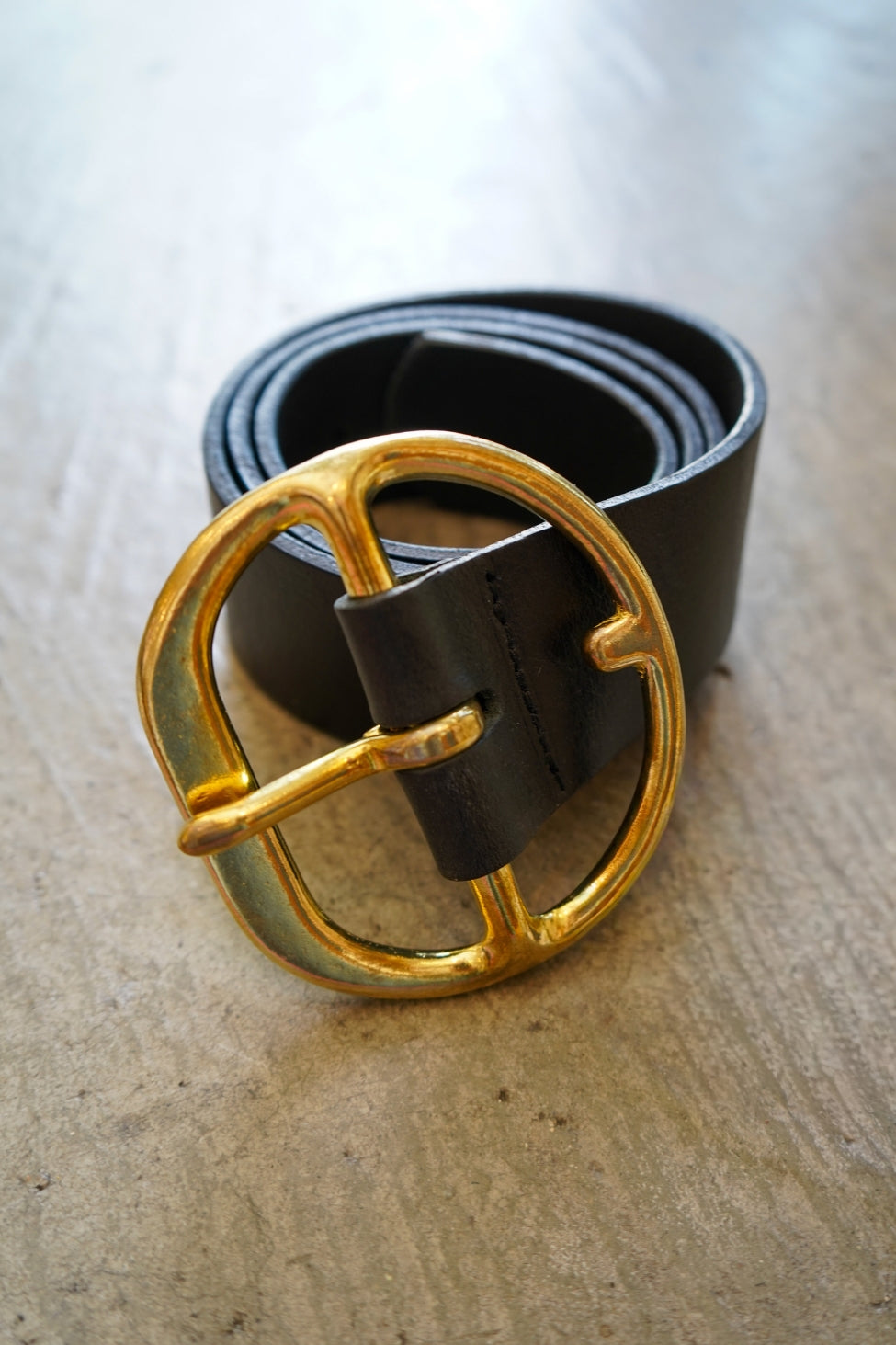 Black belt with a gold buckle on a wooden surface