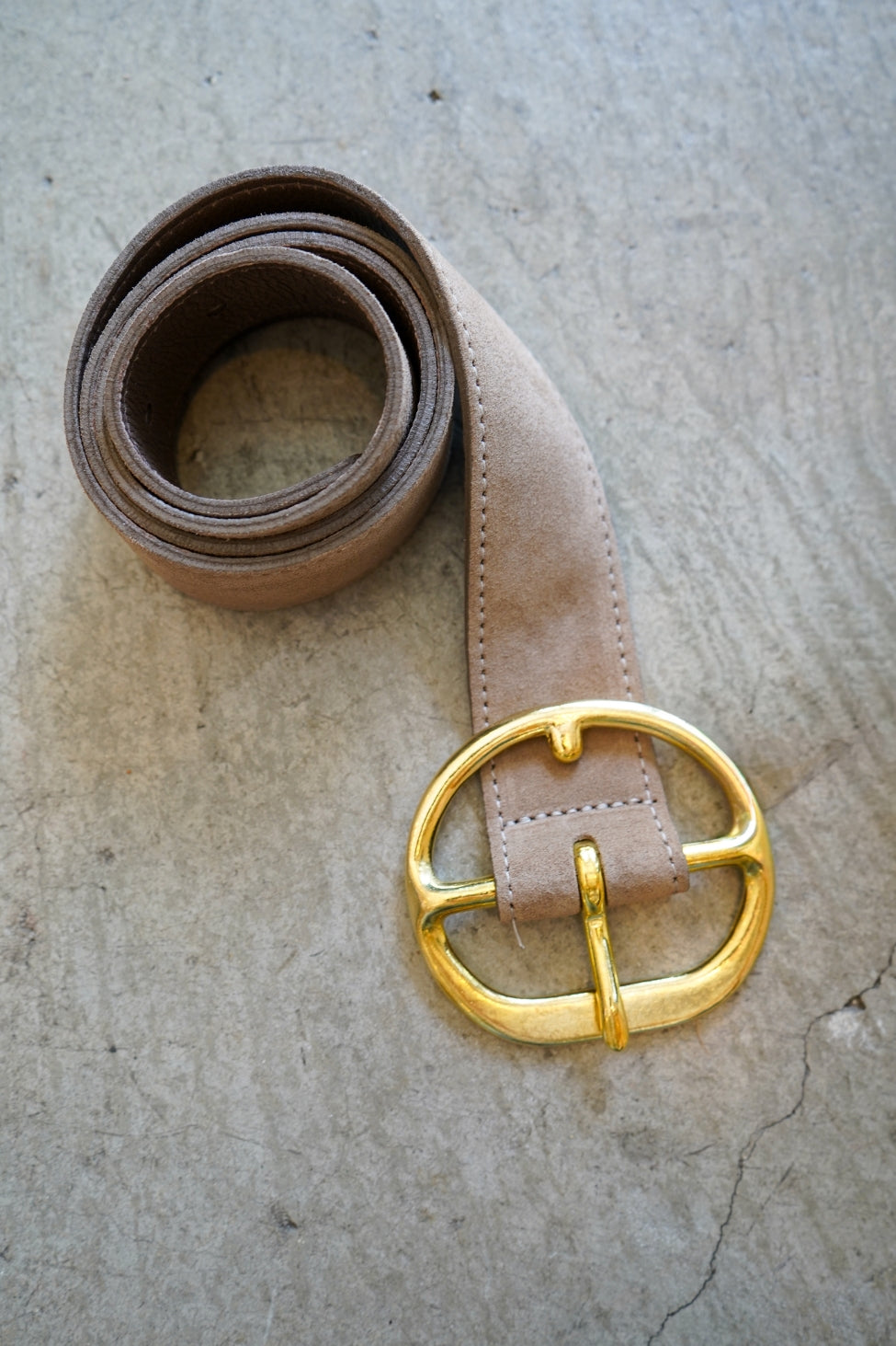 Brown belt with a gold buckle on a textured surface