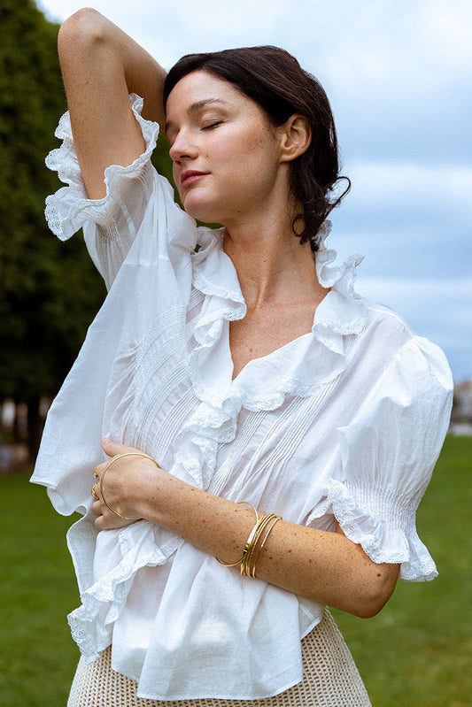 Woman wearing a white blouse with ruffled sleeves outdoors