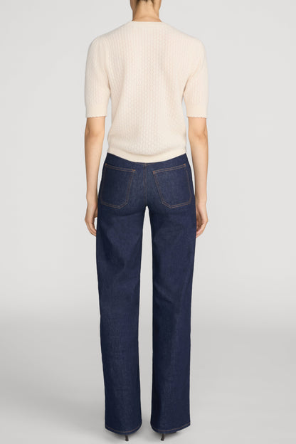 A model shown from the back wearing a cream short-sleeve ribbed knit top and Le Slim Palazzo Pintuck Pocket jeans in color rinse against a light gray studio background.