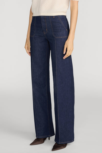 A model wearing Rinse colored Le Slim Palazzo Pintuck Pocket jeans, styled with a cream ribbed top and brown pointed-toe heels, against a light gray studio background.