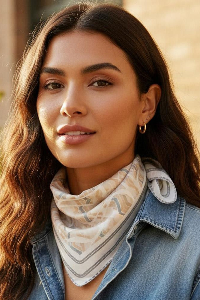 Beige tribal print bandana worn at neck, geometric motif on lightweight scarf