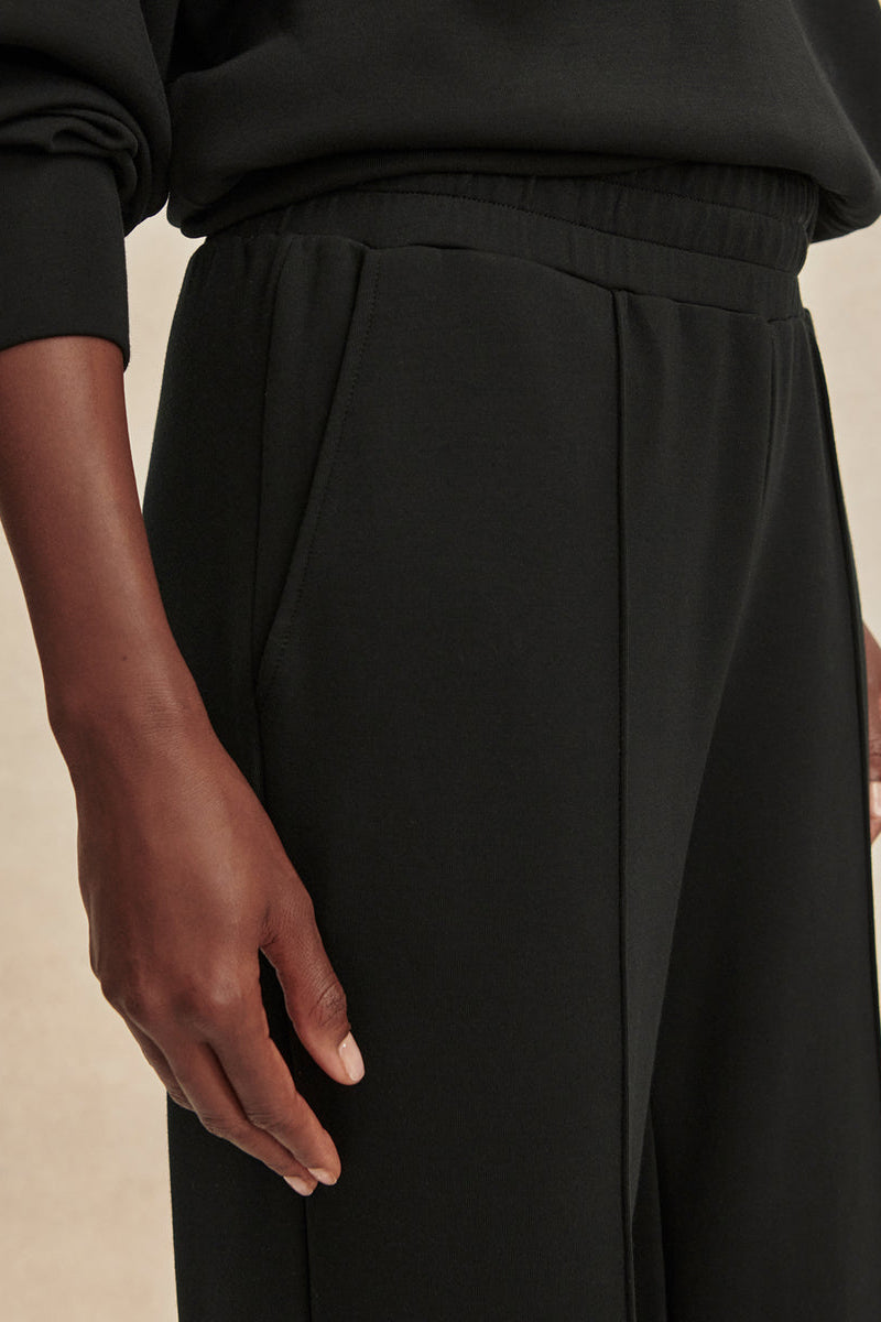 Black wide-leg pants close-up of elastic waistband and center front seam