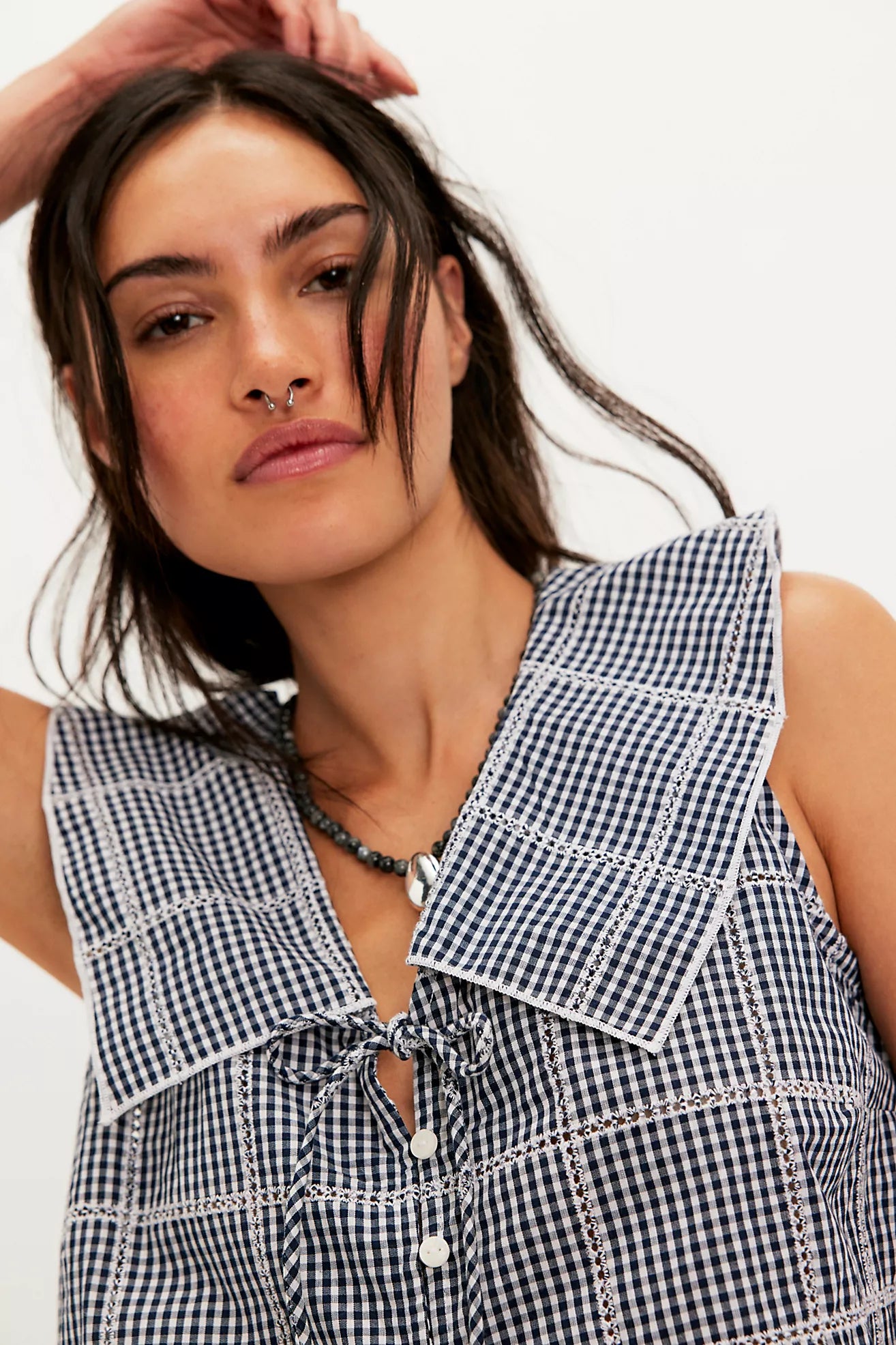 Woman wearing a black and white checkered sleeveless top with a plain background
