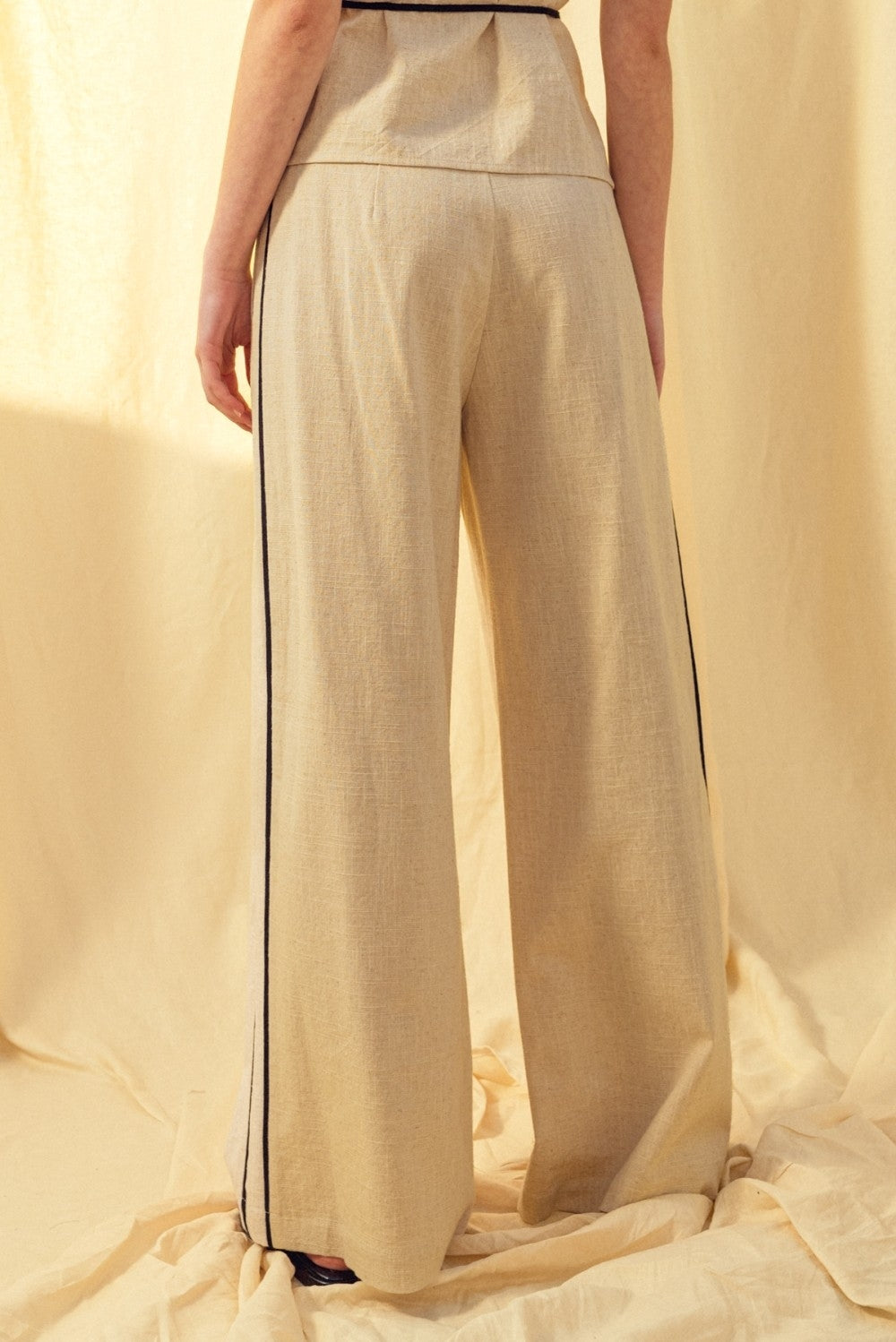 Oatmeal linen trousers with black contrast piping and wide straight legs