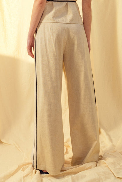 Oatmeal linen trousers with black contrast piping and wide straight legs