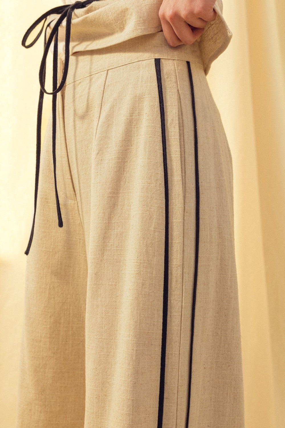 Oatmeal linen trousers with black side piping and drawstring tie waist