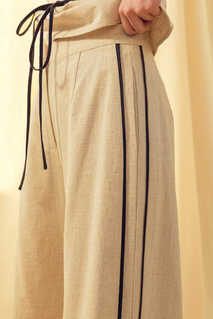 Oatmeal linen trousers with black side piping and drawstring tie waist
