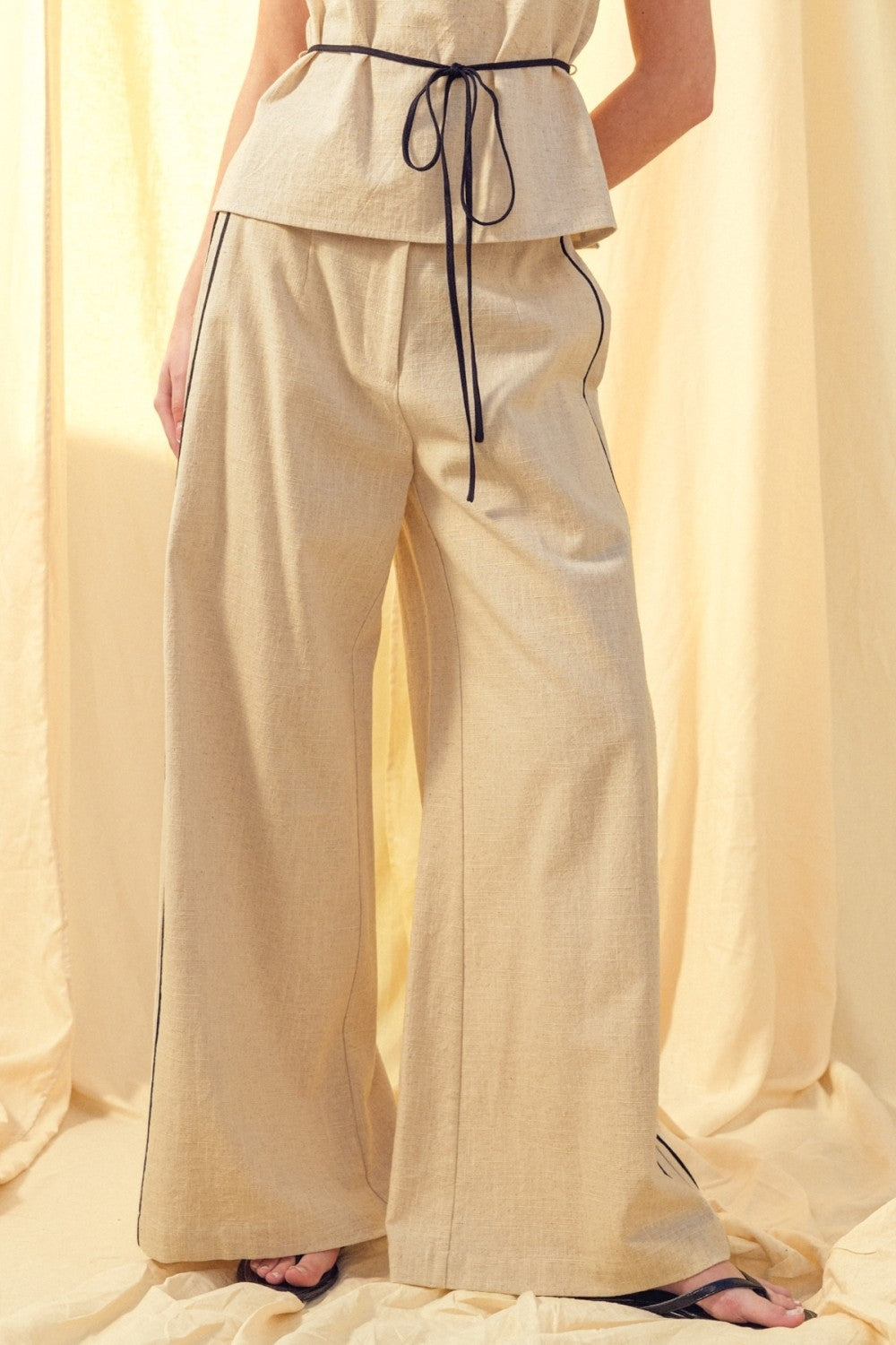 Linen trousers with black contrast piping, drawstring waist and wide-leg fit