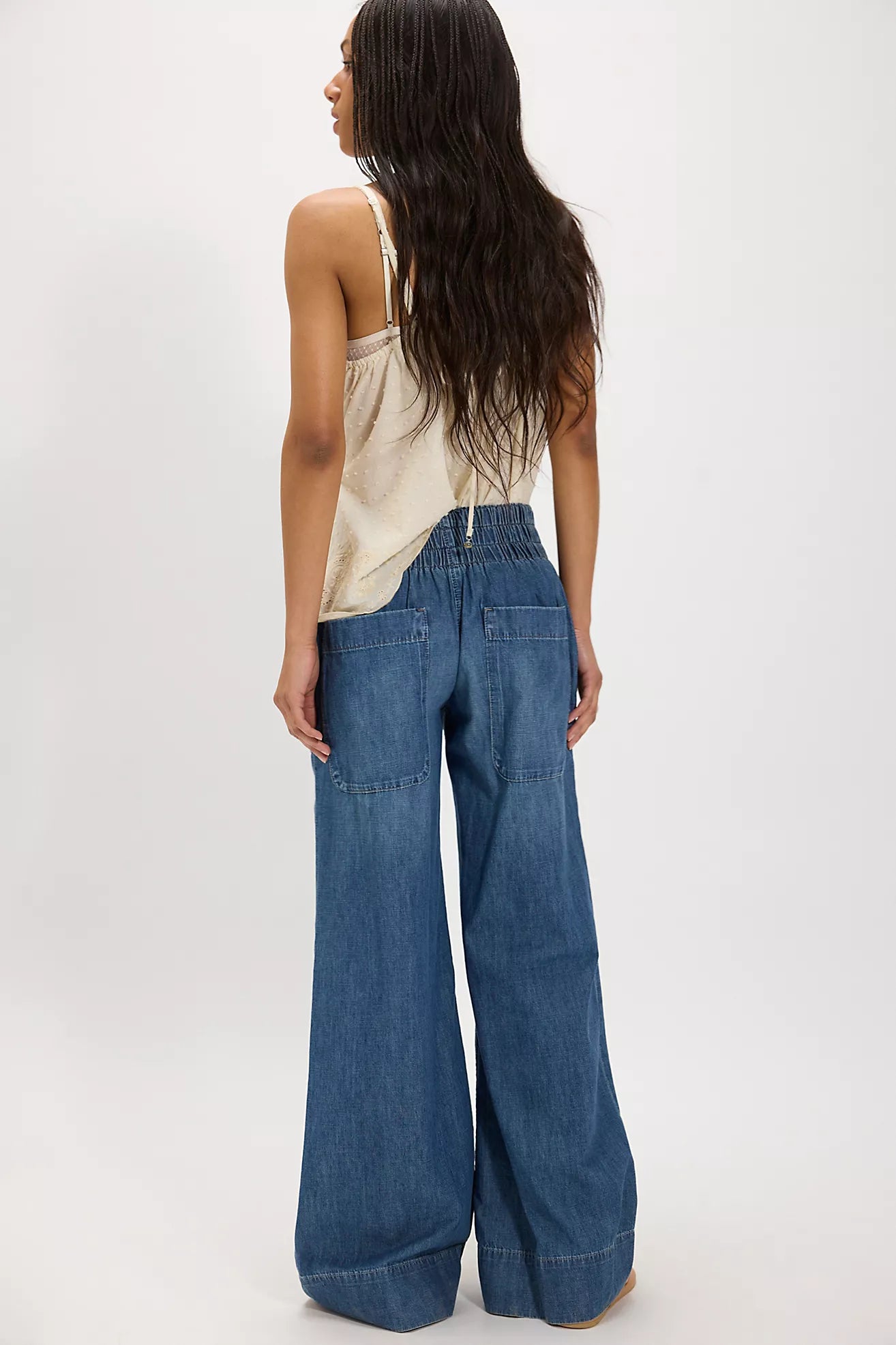 Woman wearing a beige top and cobalt breezy denim pull on wide-leg blue jeans on a white background