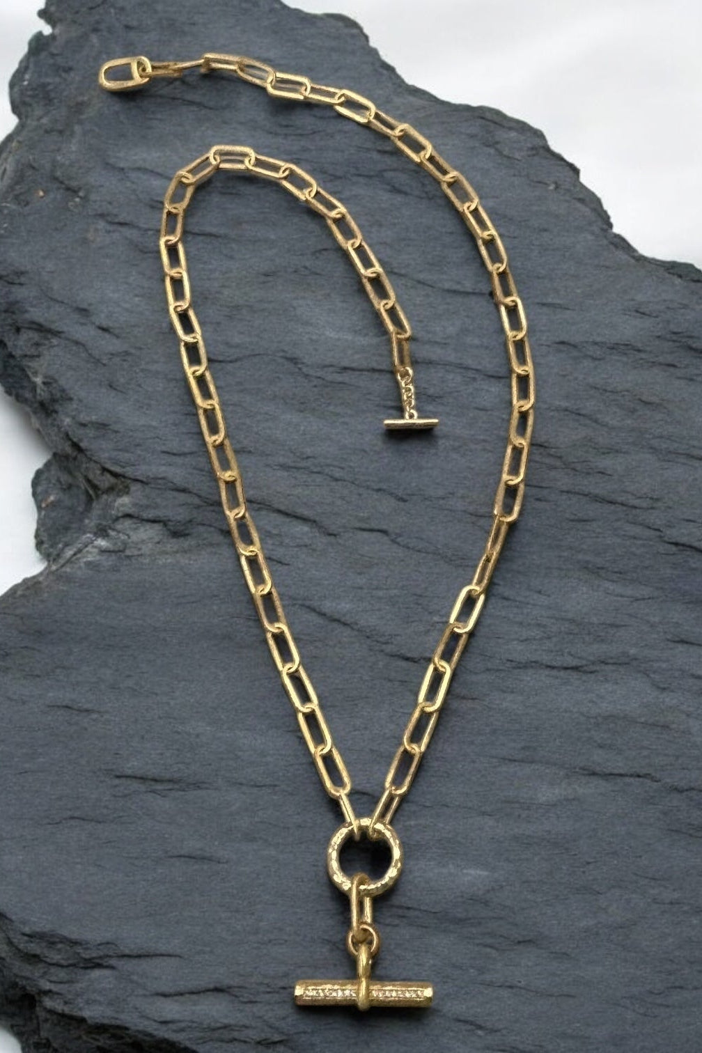 Gold toggle necklace with long oval link chain, circular toggle, and rectangular bar pendant