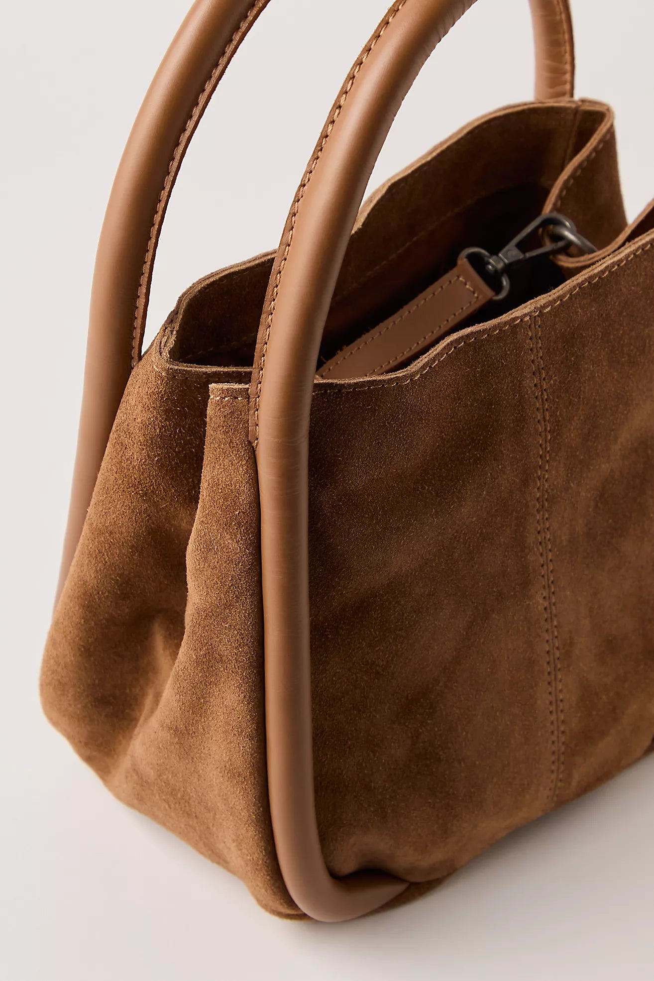 Cognac suede handbag with handles on a light gray background
