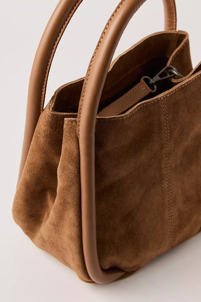 Cognac suede handbag with handles on a light gray background