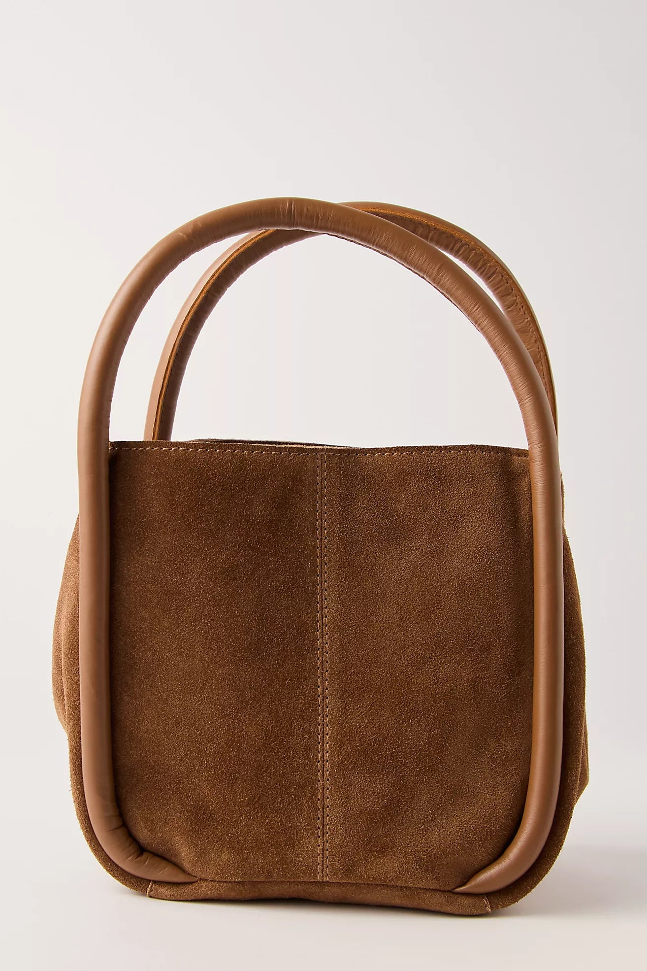 Cognac leather handbag with curved handles on a light gray background