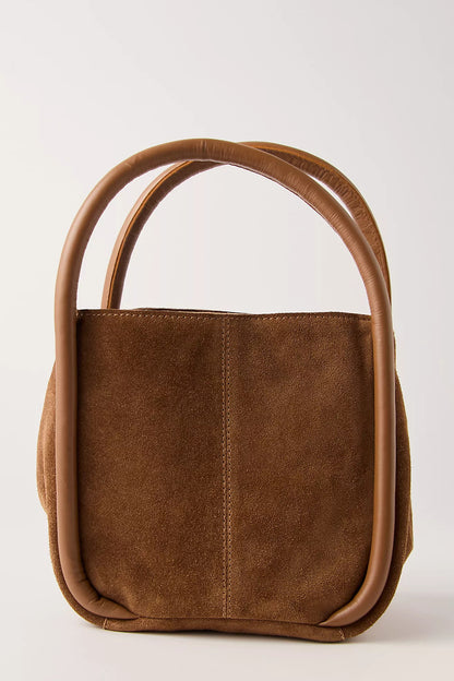Cognac leather handbag with curved handles on a light gray background