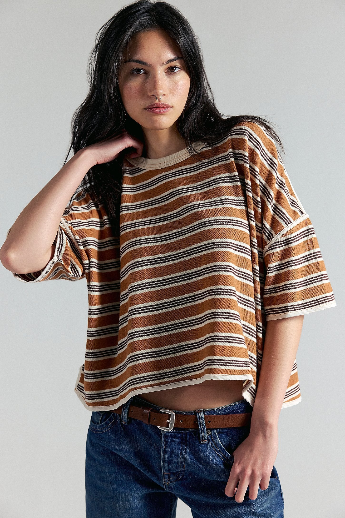 Woman wearing a striped shirt and jeans against a plain background