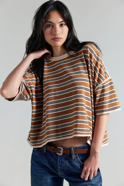 Woman wearing a striped shirt and jeans against a plain background