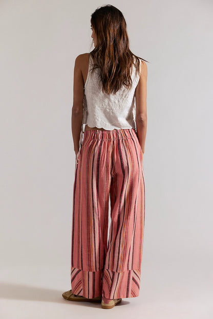 Woman wearing a white sleeveless top and red striped pants on a plain background