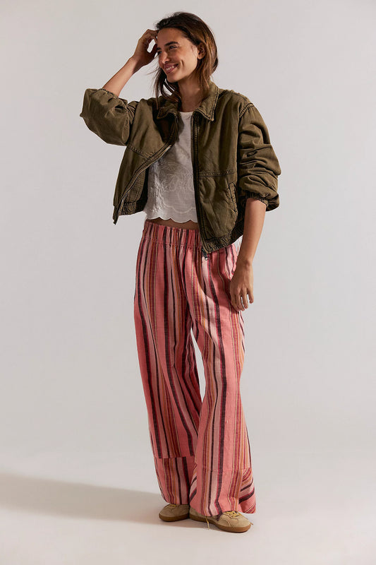 Woman wearing a green jacket, white shirt, and pink striped pants on a white background