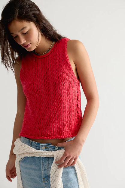 Woman wearing a red sleeveless knitted top against a plain background