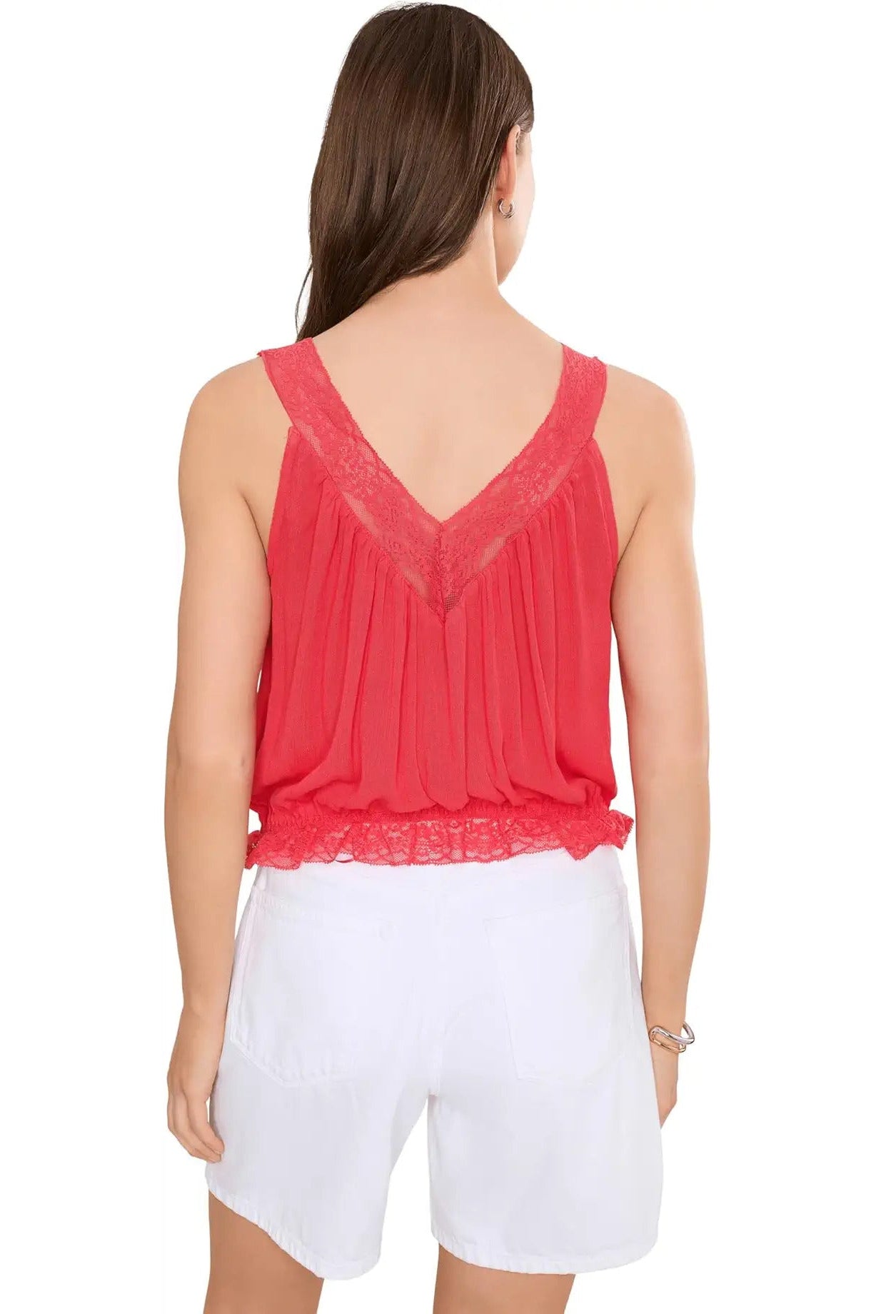 Woman wearing a red lace top and white shorts on a white background