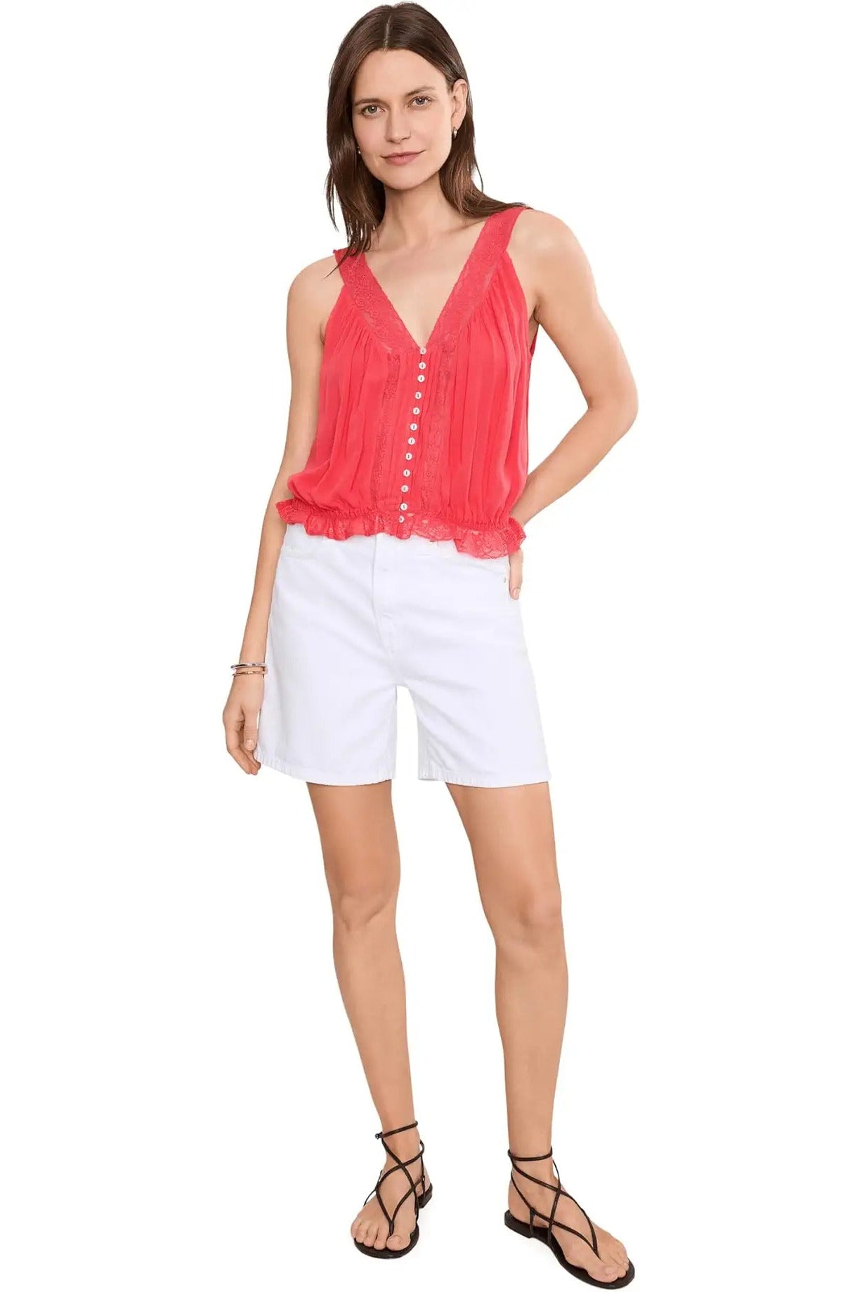 Woman wearing a coral sleeveless top and white shorts on a white background