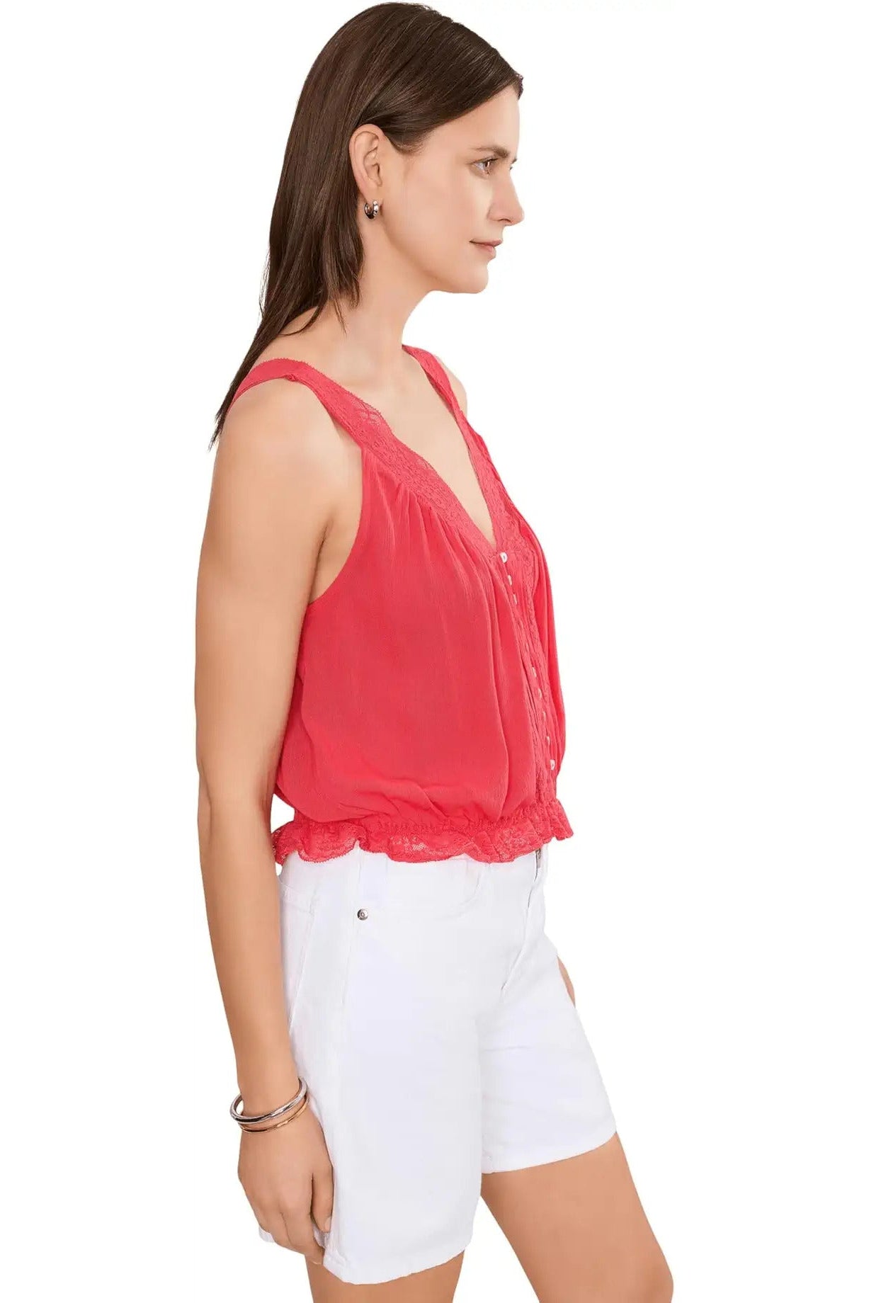Woman wearing a red sleeveless top and white shorts on a white background