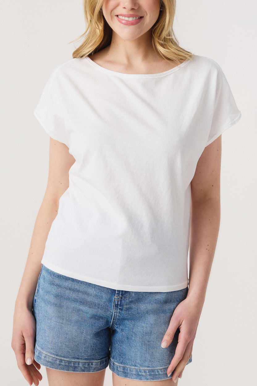 Woman wearing a white top and blue shorts on a plain background