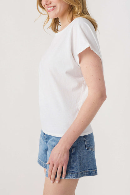 Woman wearing a white t-shirt and denim shorts on a plain background