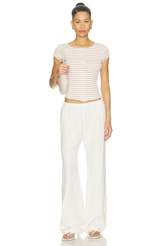 Woman wearing a striped shirt and white pants on a white background