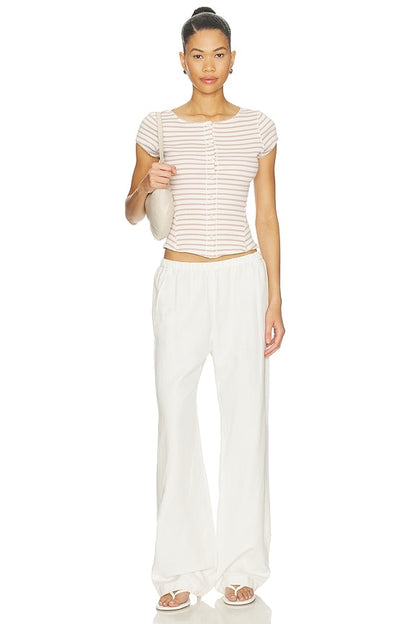 Woman wearing a striped shirt and white pants on a white background